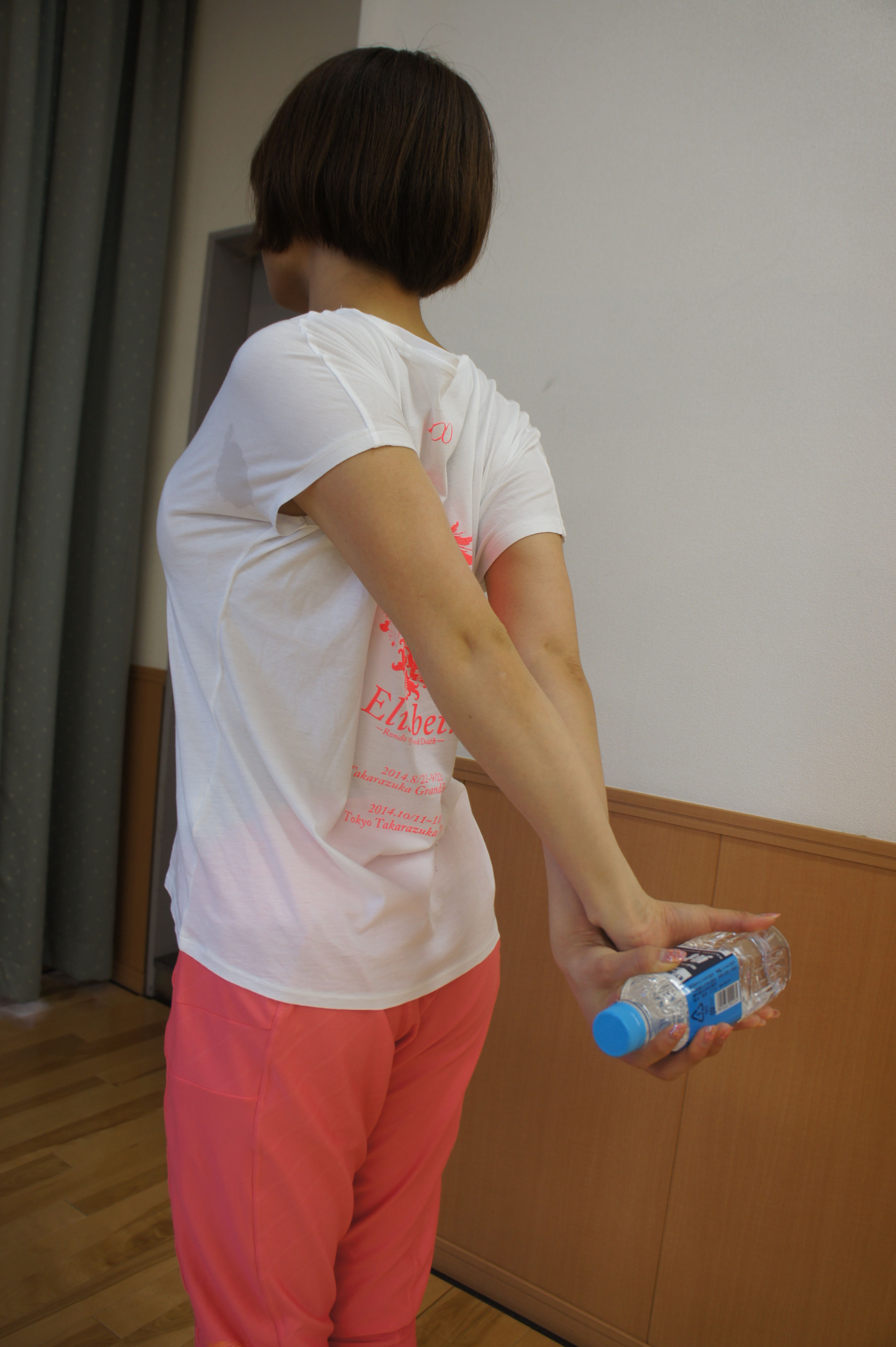 ペットボトルを後ろの手でクロスさせて持ち、ググっと上に引き上げ10秒間キープ