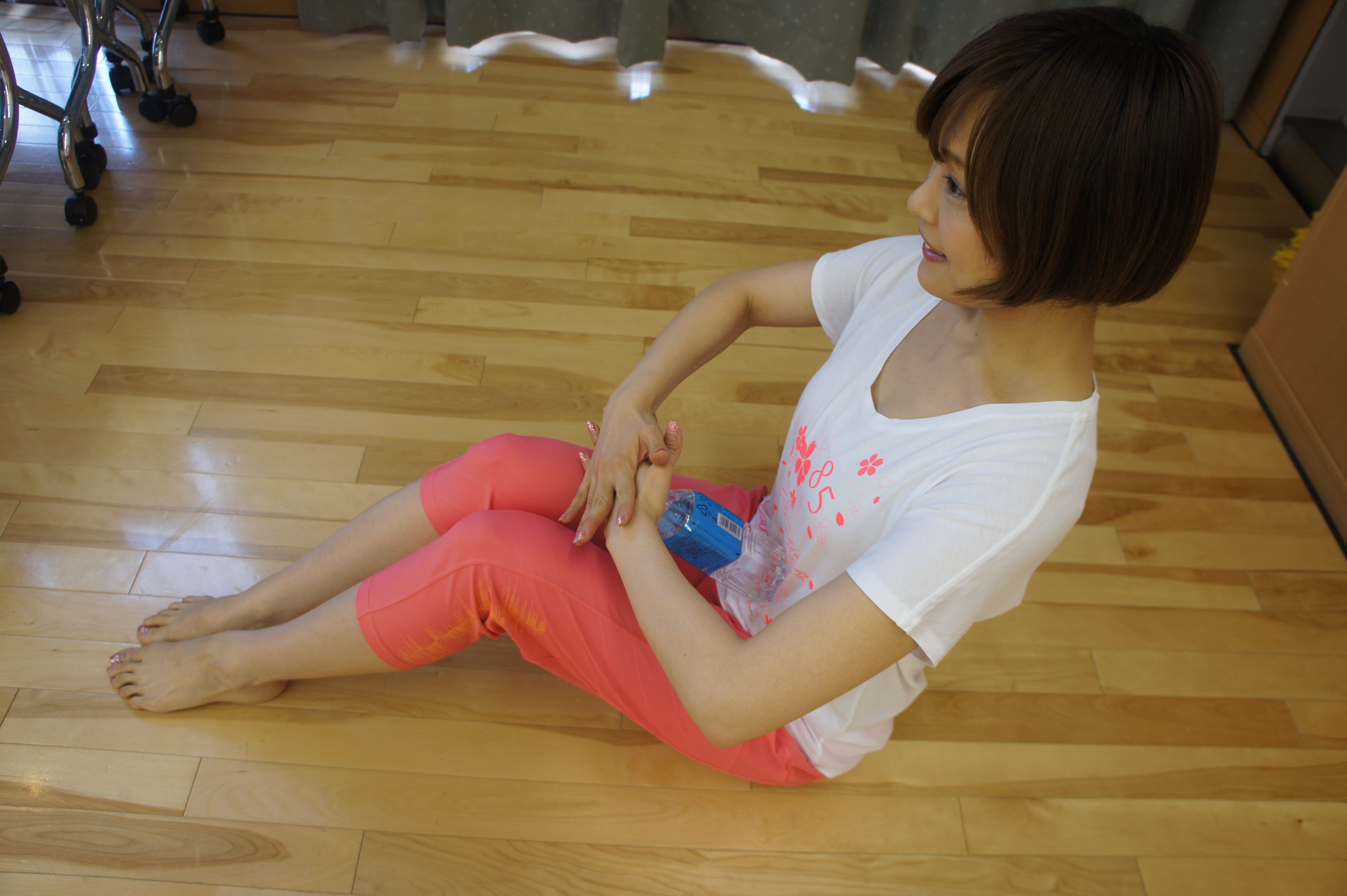 床に座り、膝を立てた状態でペットボトルをお腹にあてる