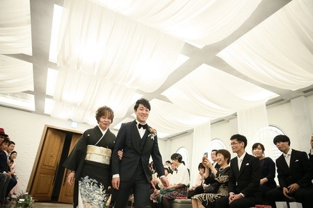 ある新郎とその母親がバージンロードを歩くひとコマ