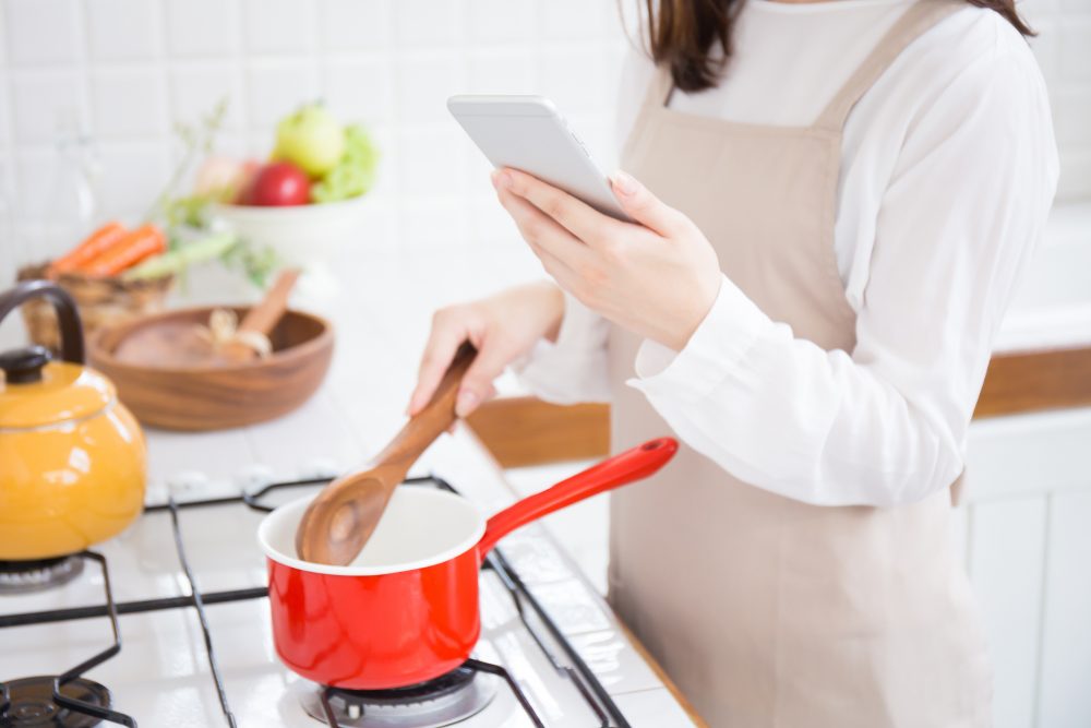 スマホを見ながら料理する女性