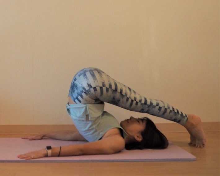 両足を持ち上げ、つま先を頭の先の床につける