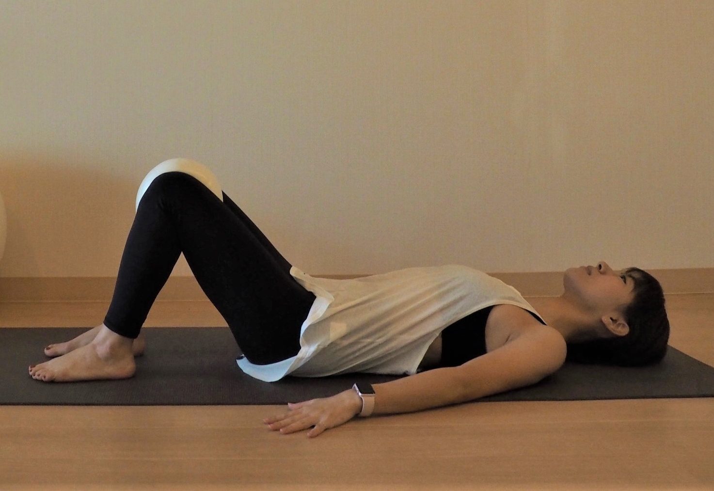 床に仰向けになりひざを立てたら、ひざとひざの間にクッションを挟む