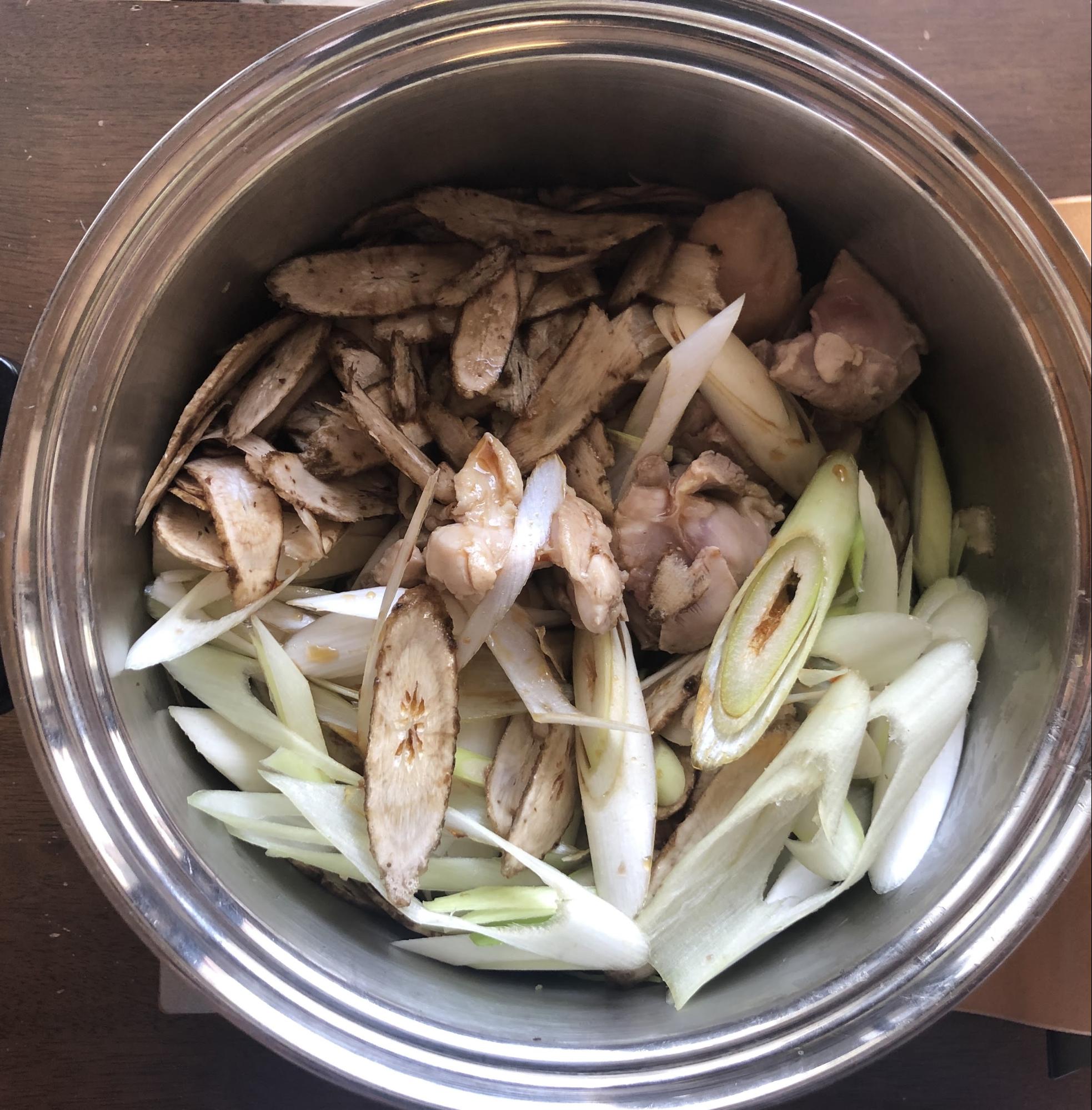 鶏もも肉が白くなってきたら、ゴボウ、長ネギ、すき焼きのタレを入れる。