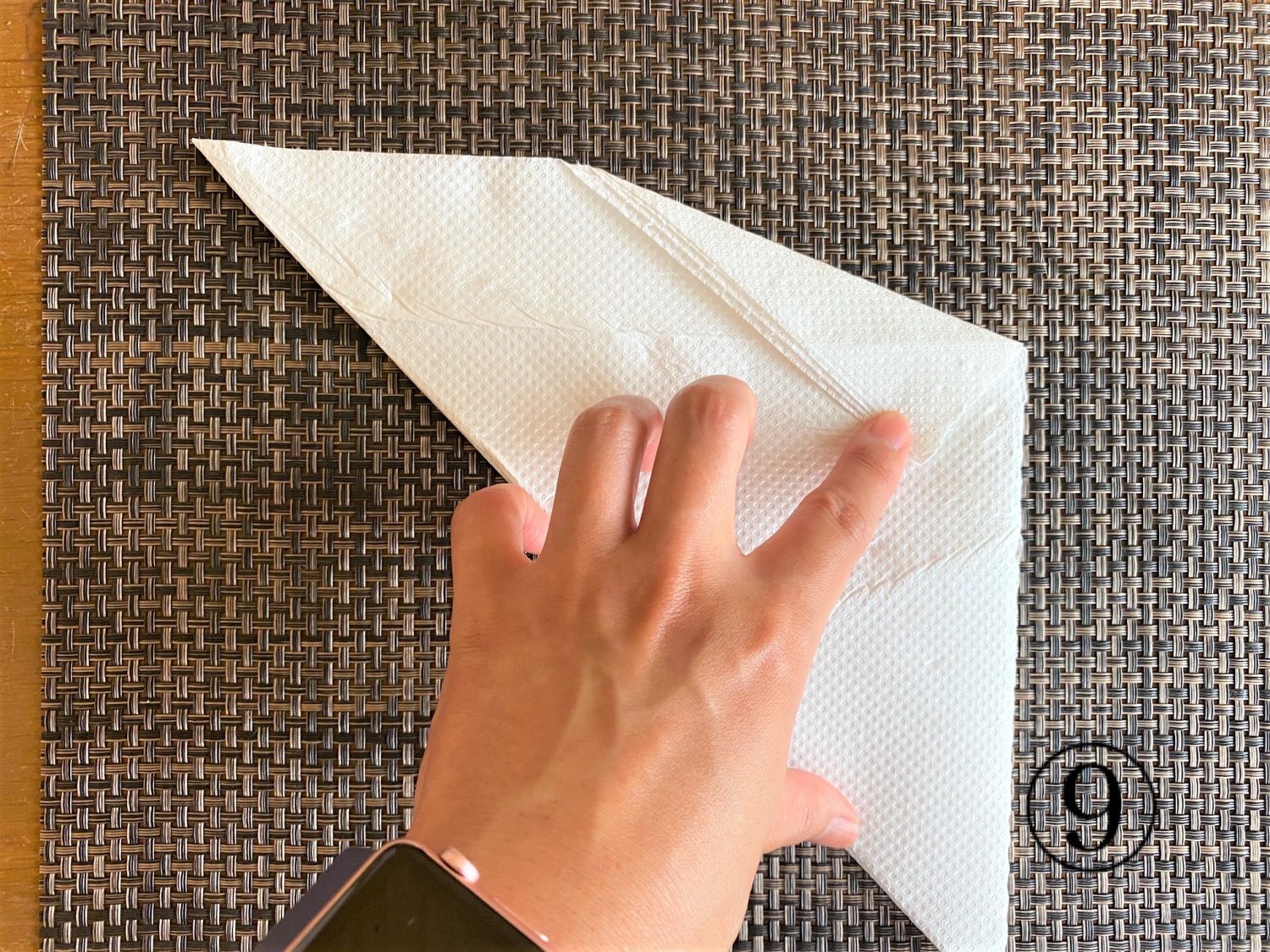 (9)その三角形の頂点部分に人差し指をあてながら、さらに大きく折る