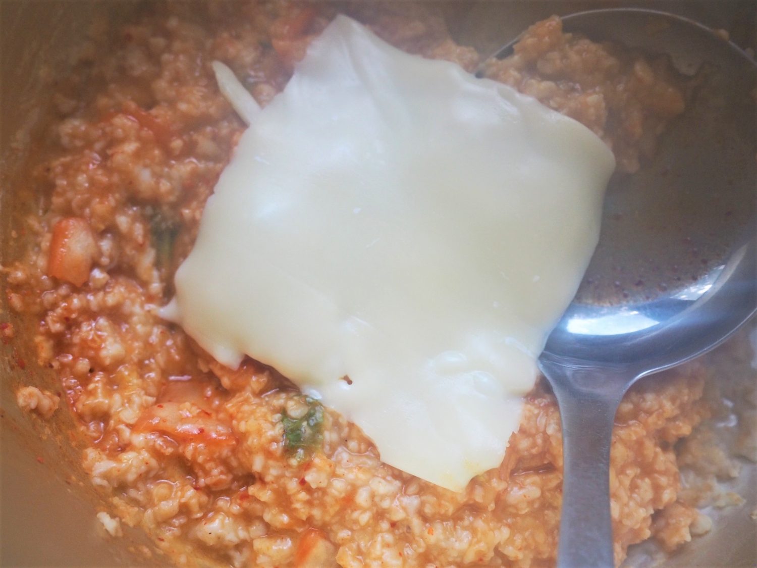 （2）とろみがついてきたらキムチとキムチの素を加え、最後にチーズを加えて煮込む2