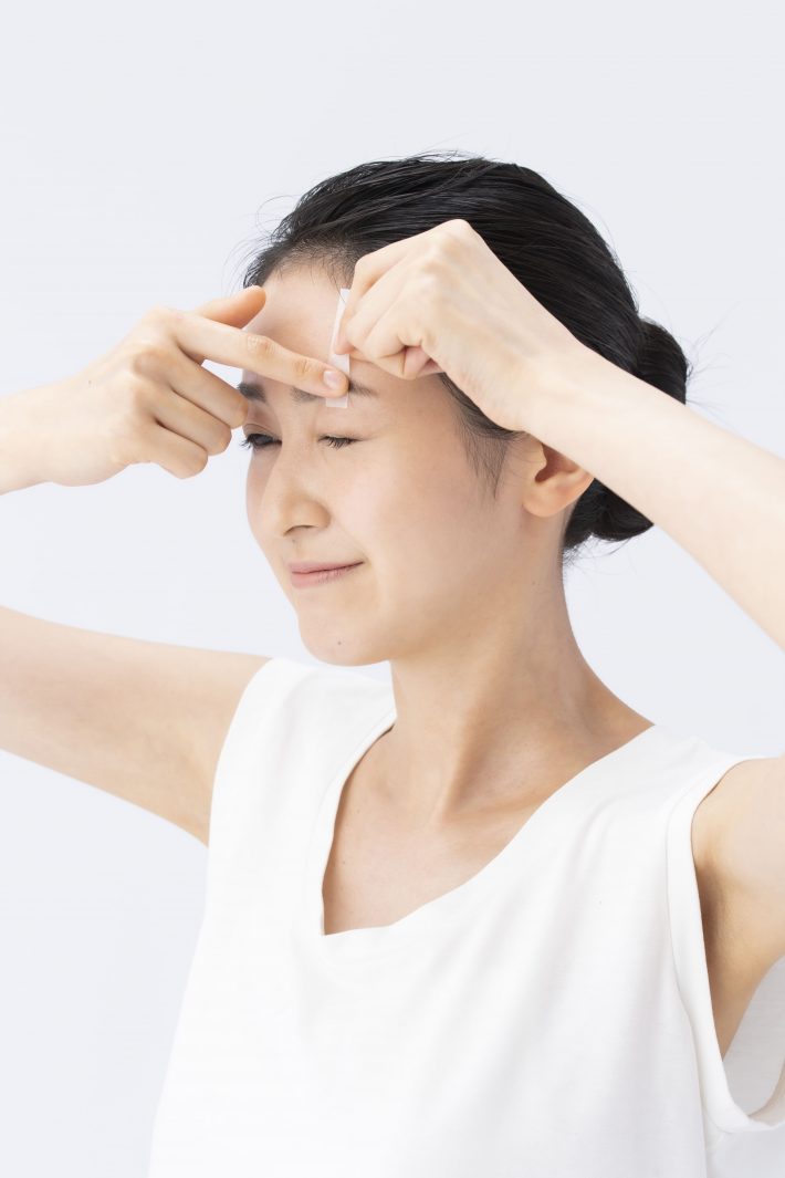 ②目をつむり、テープの端を眉毛の下に貼る。