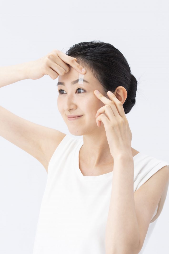 ③片手でまぶたを引き上げながら、まぶたを軽くしてテープを貼る。まばたきができる程度に。