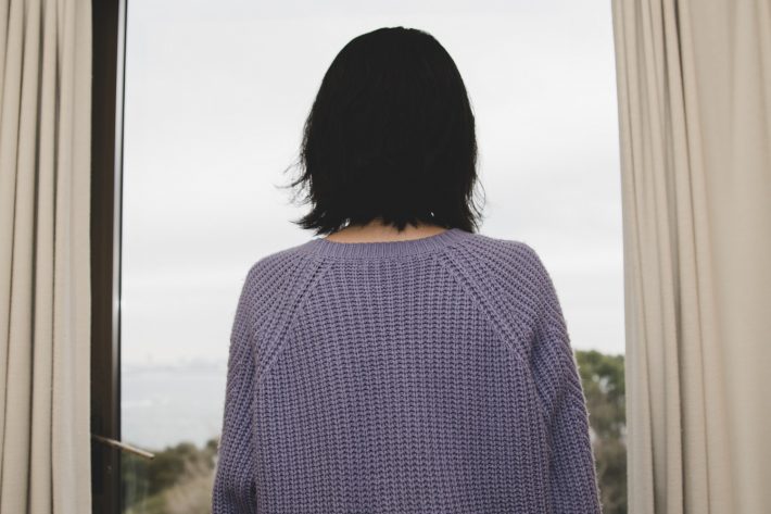 窓から外を眺める女性