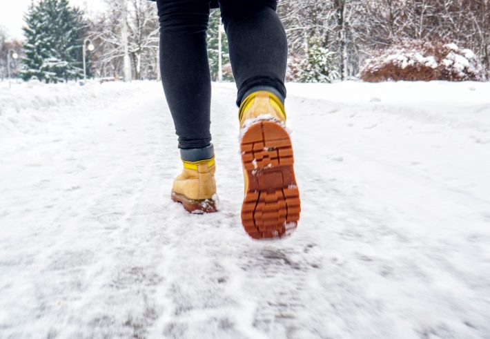 雪の中を薄着で歩く女性