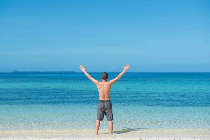 ビーチで両手を上げる男性
