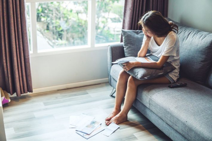 足元の請求書を見つめる女性