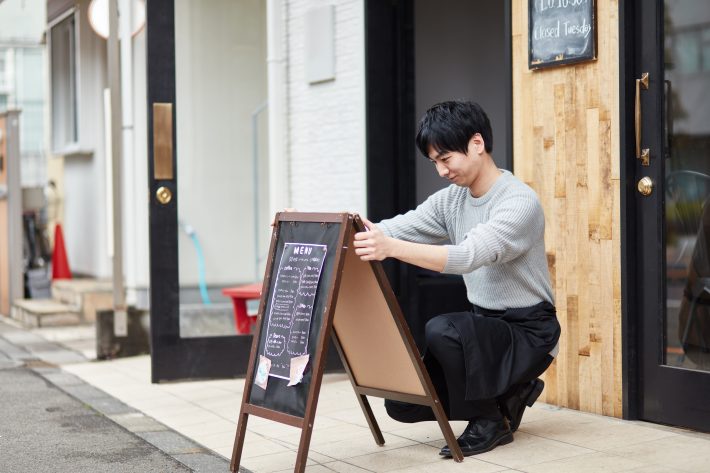 看板を出すカフェ店員