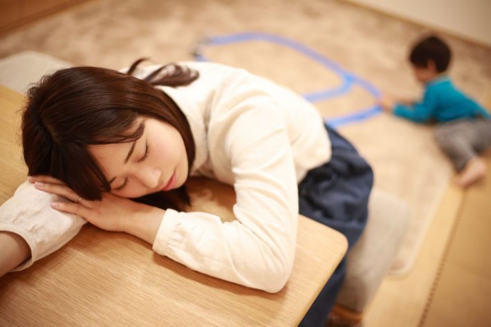 子育てに疲れて居眠りする母親