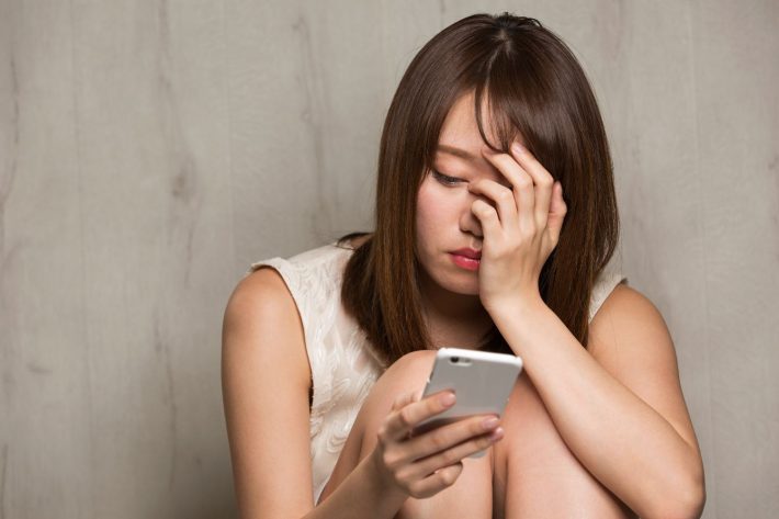 スマホを見て悩む女性