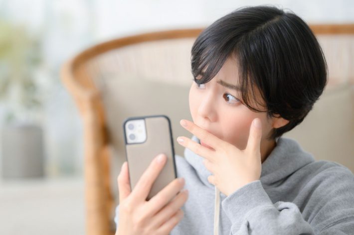 スマホを見て驚く女性