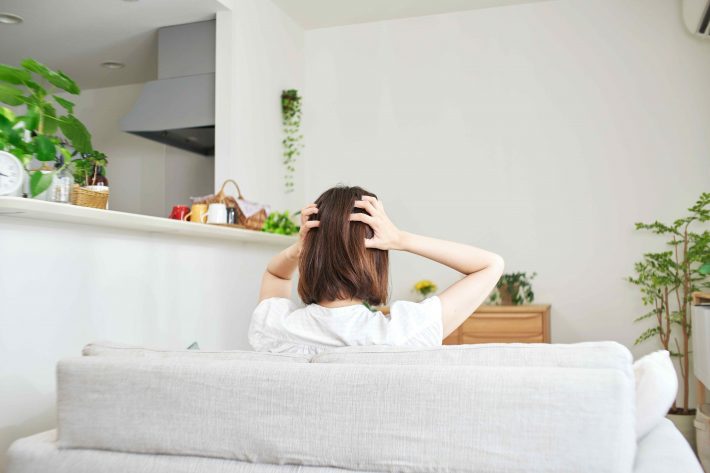 リビングで頭を抱える女性の後ろ姿