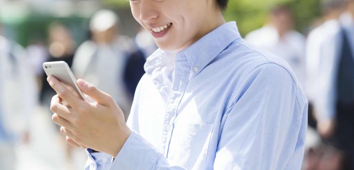 渋谷スクランブル交差点でスマホを見て笑みをこぼす男性