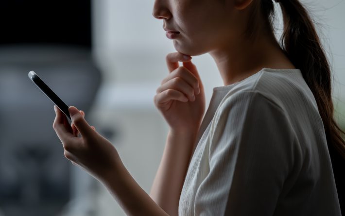 スマホを見て考え込む女性