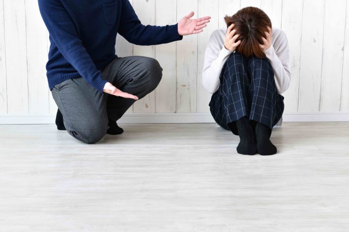 髪を掻きむしる女性と責める男性