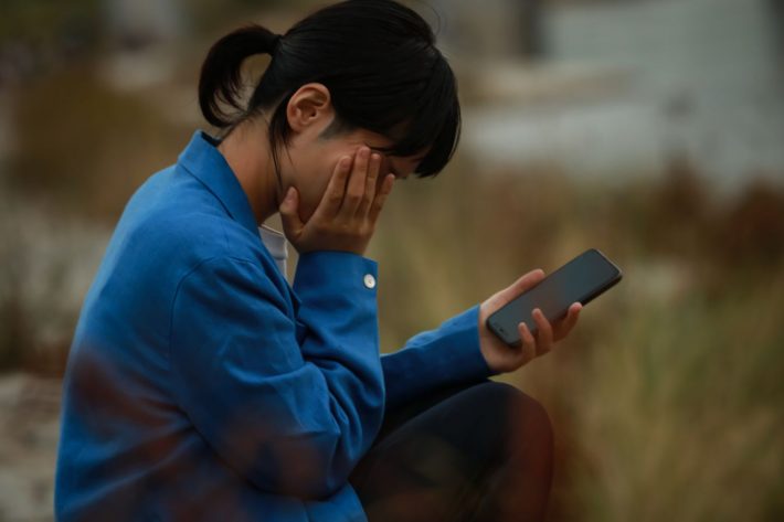 スマホを見て落ち込む女性