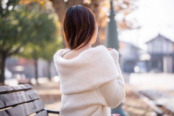 背中の空いたニットを着る女性