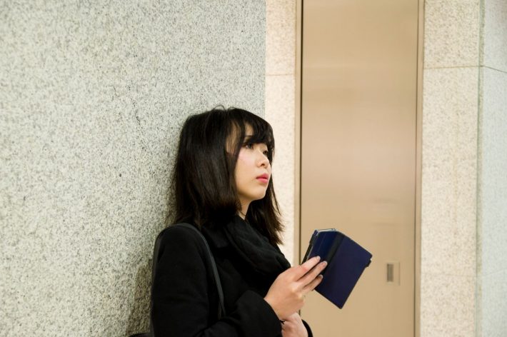 スマホを片手に待つ女性
