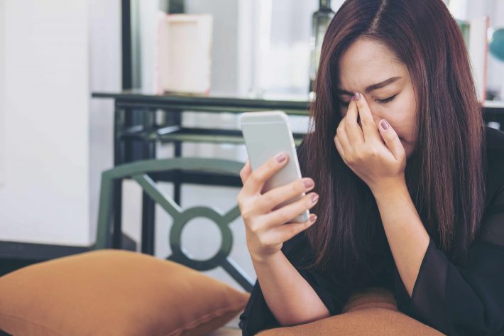 スマホを見てショックを受ける女性