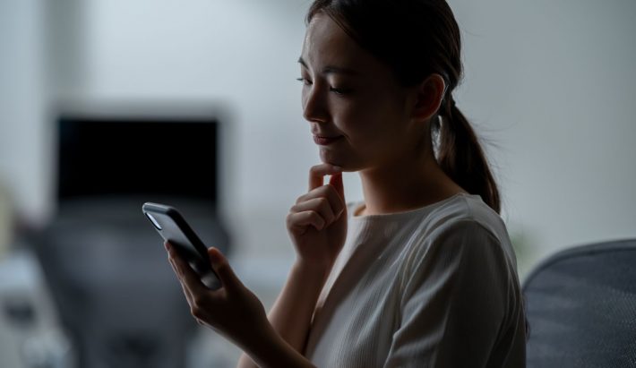 スマホを見て悩む女性