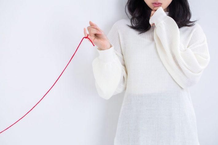 赤い糸を指につけている女性