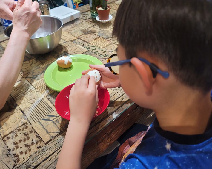 ラーメンに乗せるゆで卵の殻をむいています。専門的なグッズがなくても料理はできます。途中つまみ食いをしてもOKで、無理矢理やらせないことが肝心