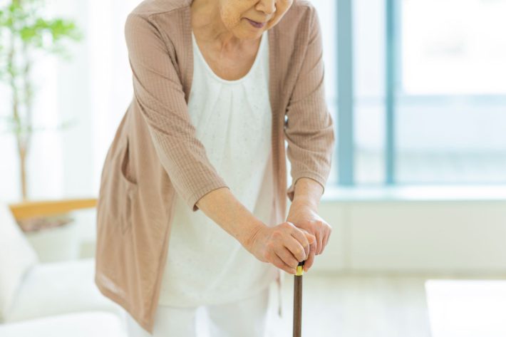 杖をついて歩くシニア女性