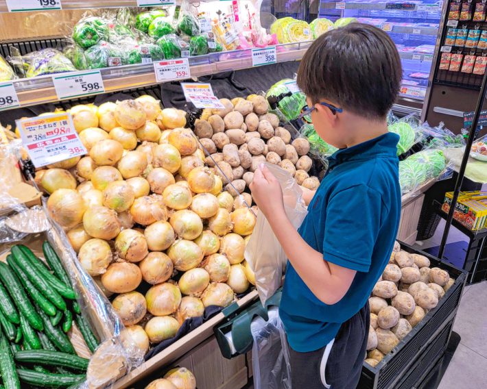 玉ねぎやジャガイモを選りすぐって3個袋に入れている息子