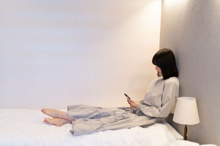 部屋でスマートフォンを使う女性