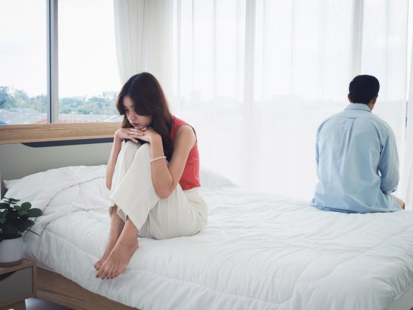ベッドで背を向けるカップル