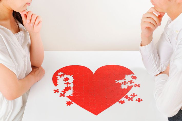 赤いハートのパズルを作っているカップル