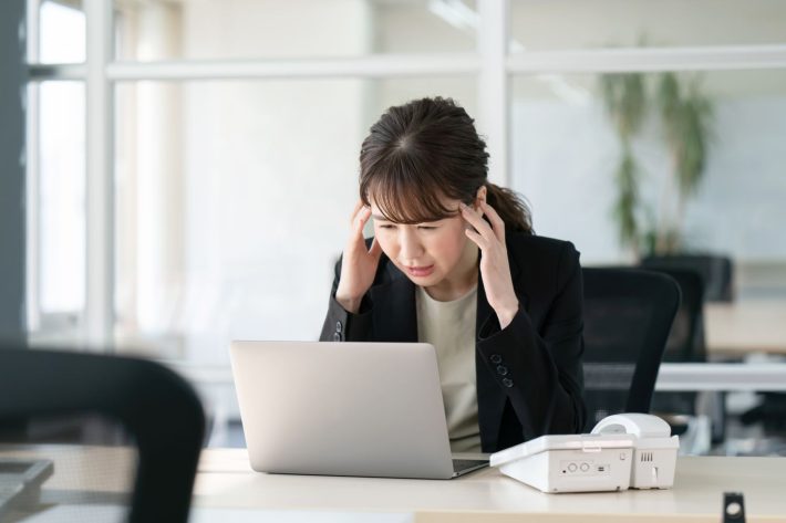 パソコンを見て頭を抱える女性