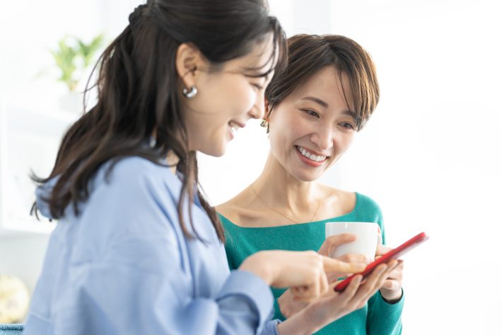 スマホを友達に見せる女性