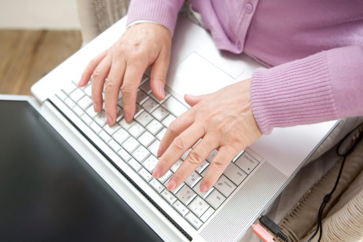 パソコンのキーボードをたたくシニア女性の手元