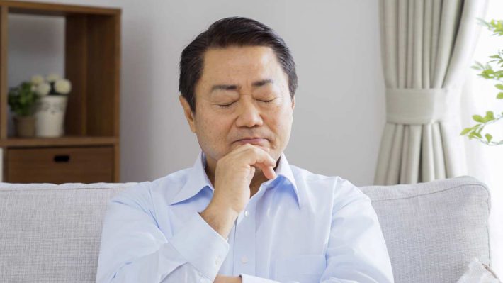 手を顎に付ける男性