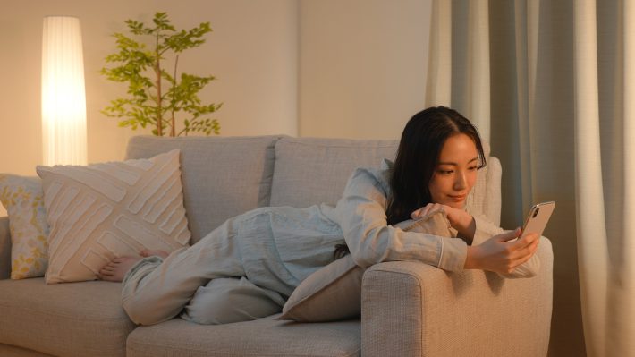 ソファーでスマートフォンを見る女性