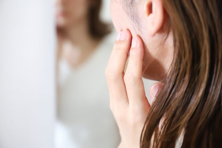 鏡で顔を見る女性