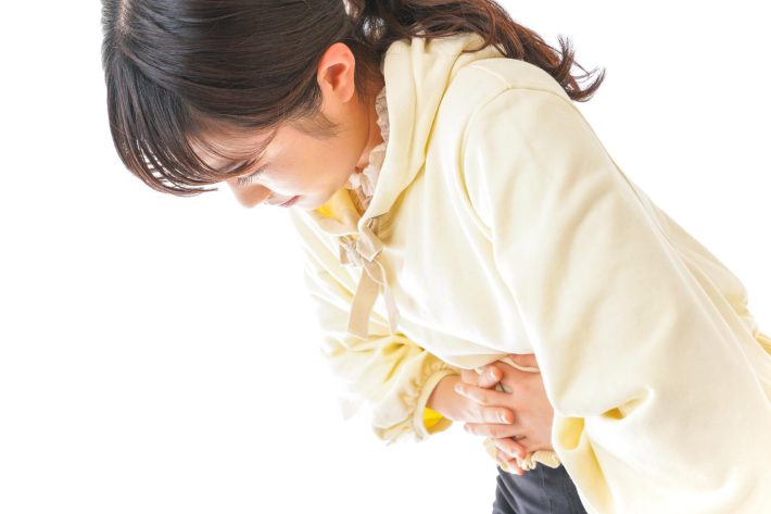 お腹をおさえる女性