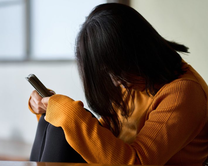 スマートフォンを見て気分が落ち込む女性