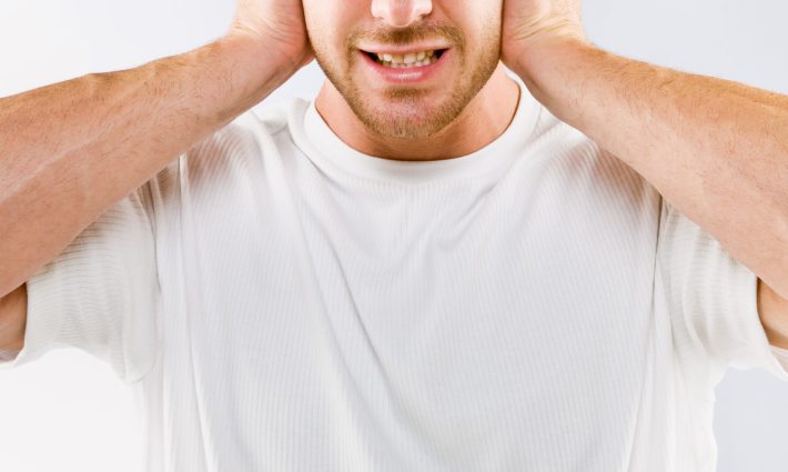 耳をふさぐ男性