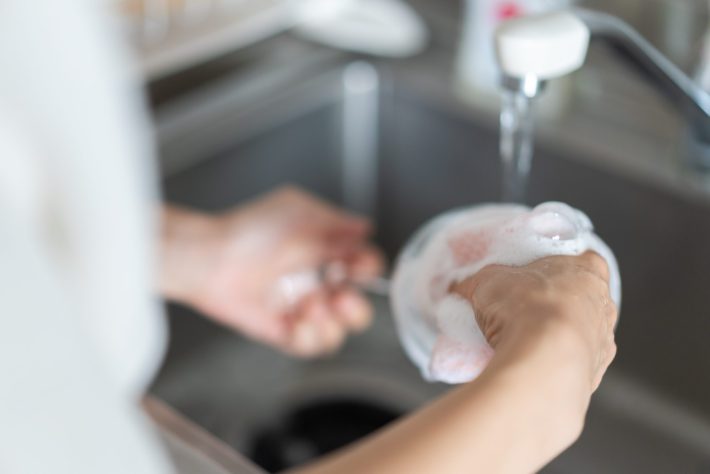 家で洗い物をする若い女性