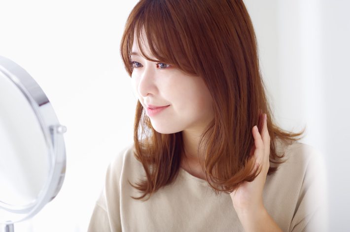 髪の毛を撫でる女性