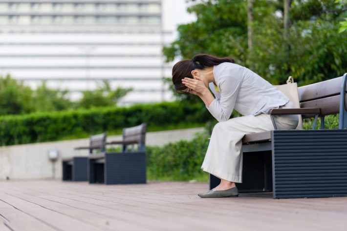 公園のベンチに座って落ち込む女性