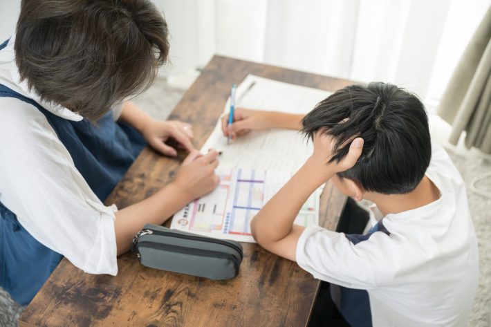 子どもに一生懸命勉強を教える母親