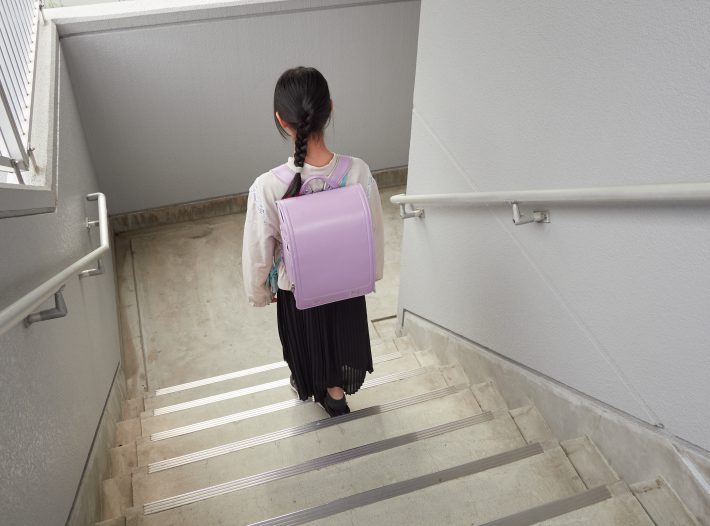 集合住宅の家から登校する小学生の女の子の様子