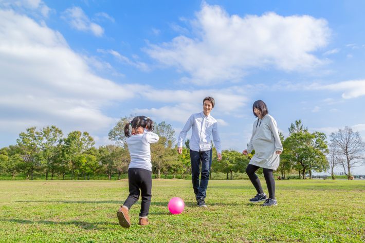 公園でボール遊びをする家族